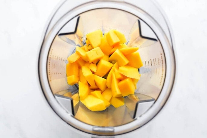 A high powered blender with chunks of mango.