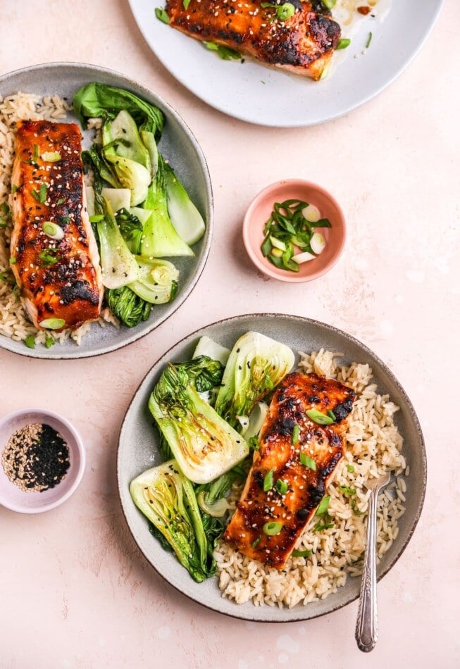Two shallow bowls each with a miso salmon filet served over a bed of rice with bok choy.