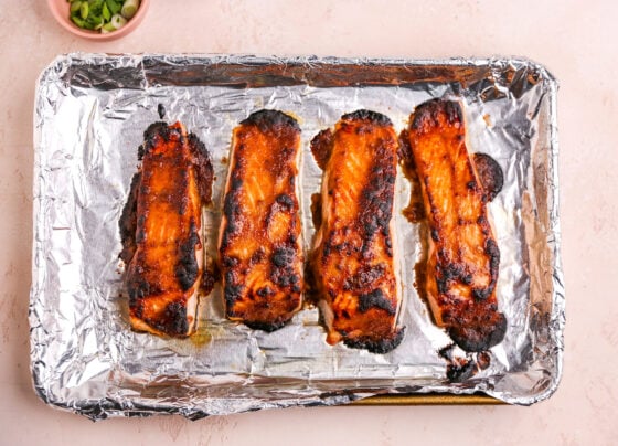 Four miso salmon on a baking sheet lined in foil after broiling.