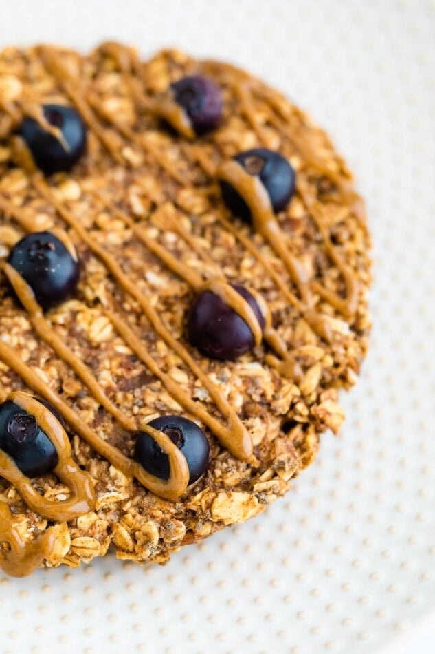 A close up of the blueberries and peanut butter drizzle on an oatmeal breakfast cookie.