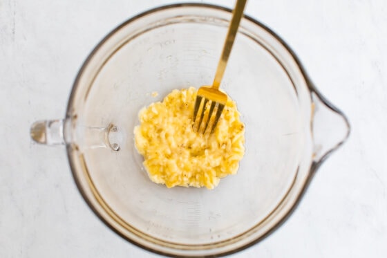 Mashed banana in a large glass mixing bowl.