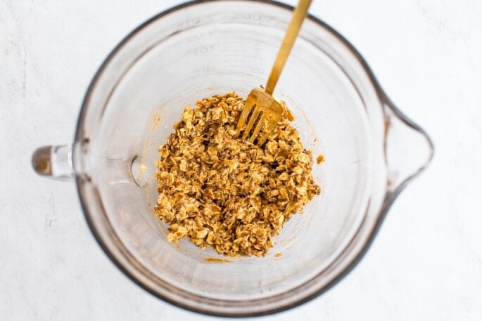 Oats, baking powder, cinnamon, maple syrup, chia seeds and almond butter mixed in with the mashed banana in a large glass mixing bowl.