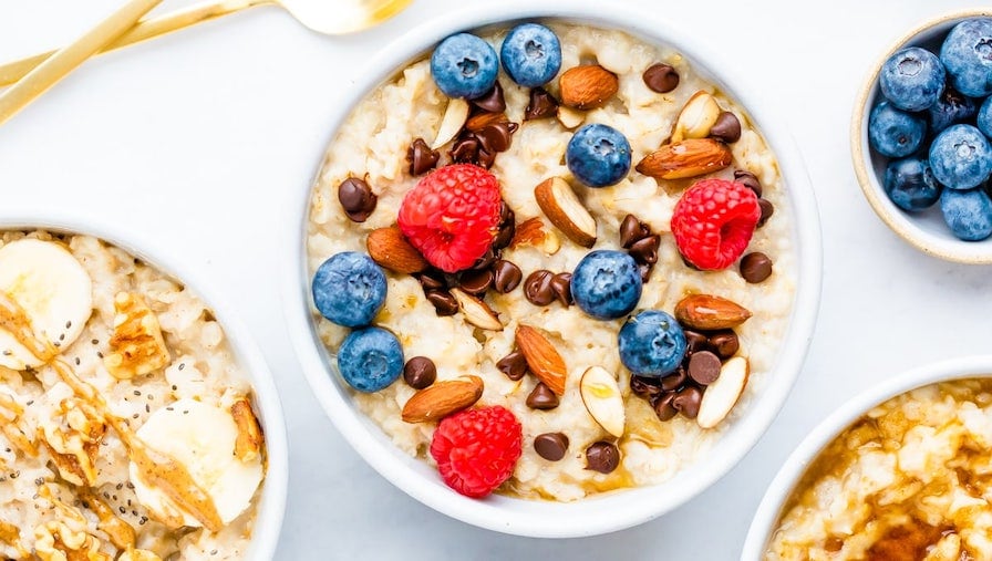 Bowl of oatmeal topped with berries, almonds and chocolate chips.