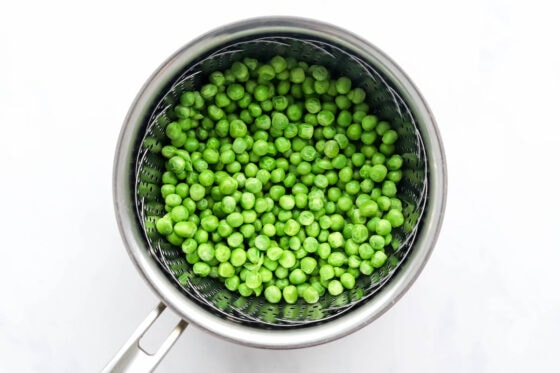 Freshly steamed peas in a pot in a steamer basket.