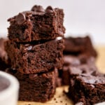 Three brownies stacked on top of one another. The top brownie has a bite taken out of it.