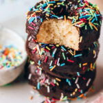 A stack of protein donuts, the top donut has a bite taken out of it.