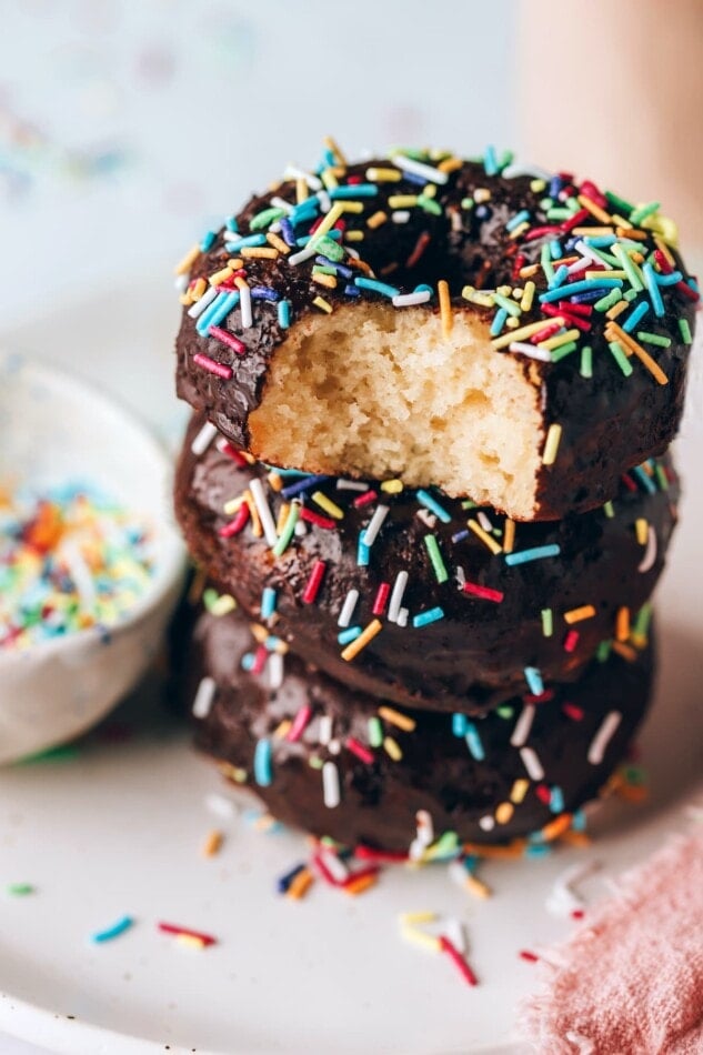 A stack of protein donuts, the top donut has a bite taken out of it.