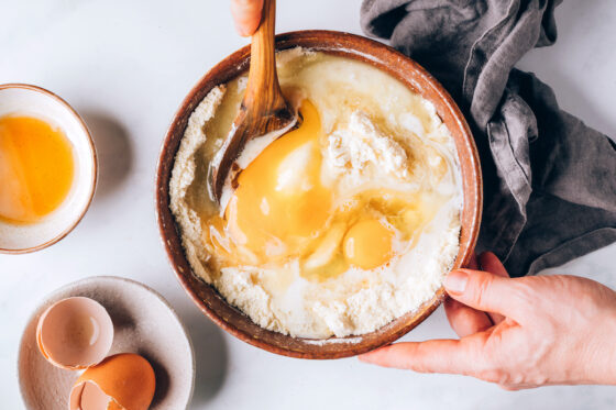 Maple syrup, eggs, coconut oil, almond milk and vanilla extract added to the flour mixture in a bowl.