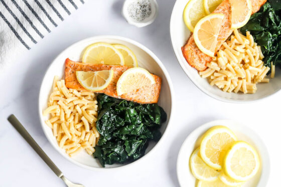 Macaroni and cheese, salmon and kale added to a bowl.