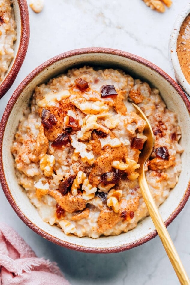 An overhead photo of a bowl containing salted date nut oatmeal. A spoon rests in the bowl.