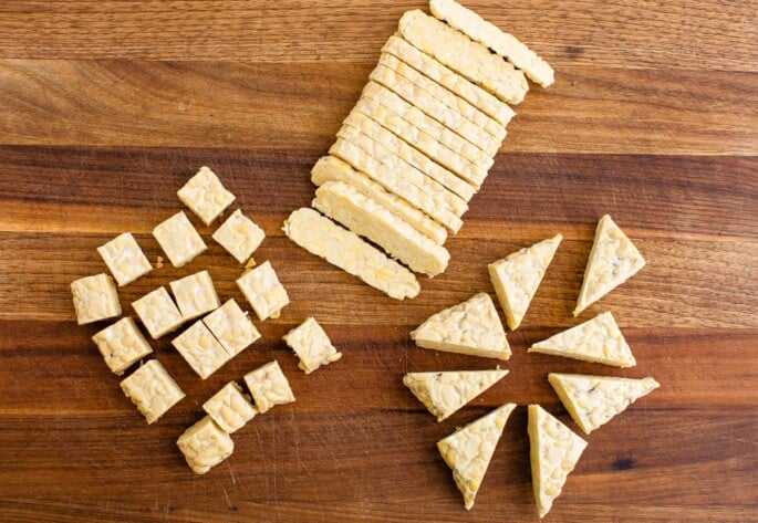 Three versions of tempeh that have been sliced, cubed, and cut into triangles.