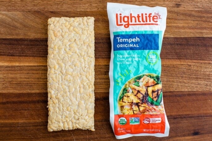Side by side tempeh rectangles. On the left, the tempeh is out of the packaging, on the right is Lightlife tempeh in the packaging.
