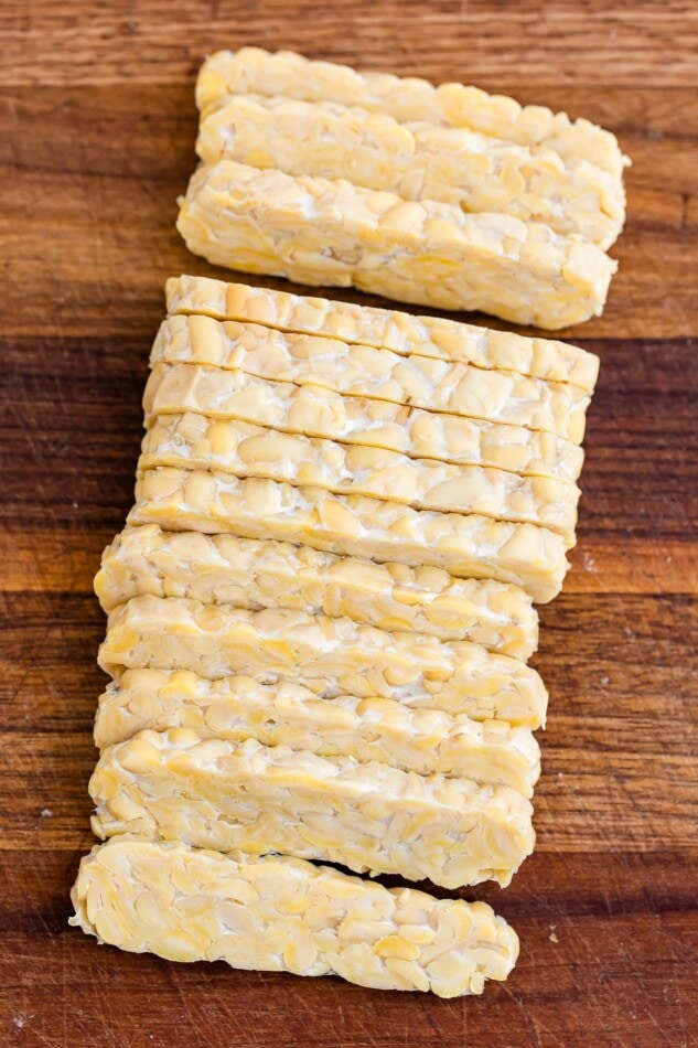 A square of tempeh that has been sliced into long, thin sections.