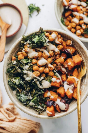 A vegan power bowl drizzled with creamy white bean dressing. A gold fork rests in the bowl.