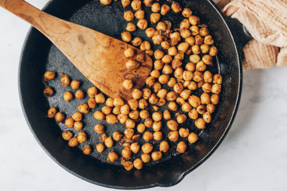 Seasoned chickpeas sautéing in a cast iron skillet.