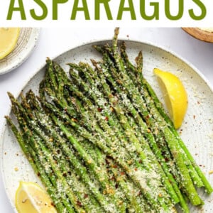 Plate of air fryer asparagus topped with parmesan, red pepper and lemon.