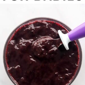 A bowl of blueberry puree with a purple spoon resting in the bowl.