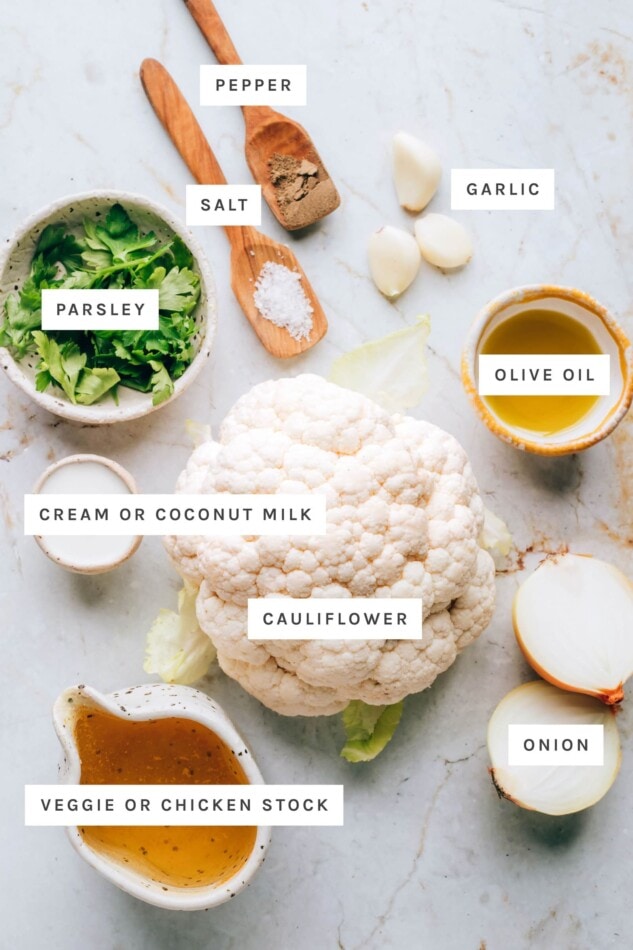 Ingredients measured out to make cauliflower soup: pepper, salt, garlic, parsley, olive oil, cream/coconut milk, cauliflower, onion and veggie/chicken stock.