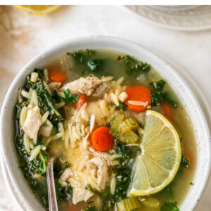 A bowl of lemon chicken orzo soup. A spoon rests in the bowl.