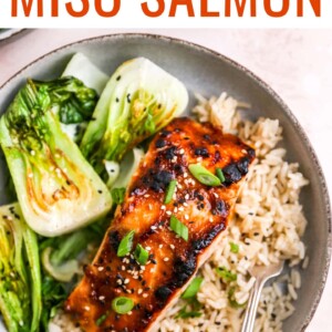 A close up of a miso salmon filet over a bed of rice next to some bok choy.