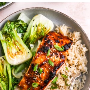 A close up of a miso salmon filet over a bed of rice next to some bok choy.