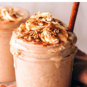 Mason jar filled with an oatmeal smoothie, topped with cinnamon, banana and oats.