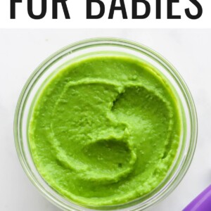 A small jar of pea puree. A purple spoon is cut out of the frame.