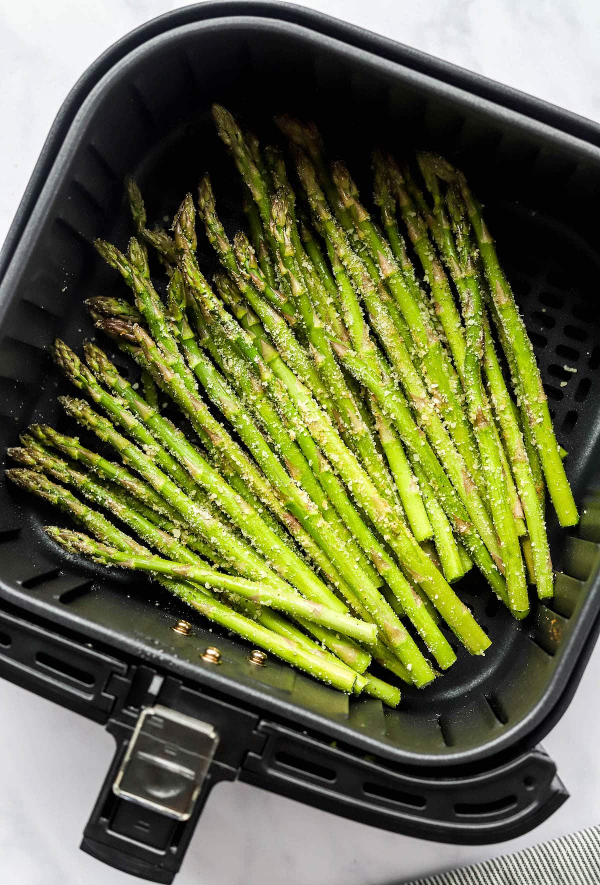 Asparagus spears in an air fryer basket.