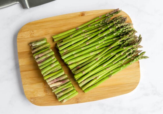 Asparagus spears on a cutting board with the bottoms removed.
