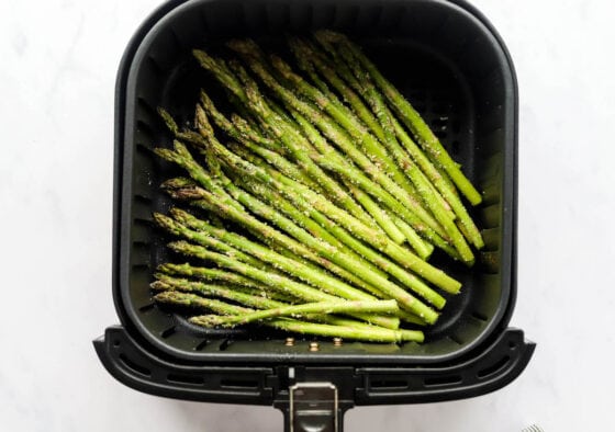 Asparagus spears in an air fryer basket.