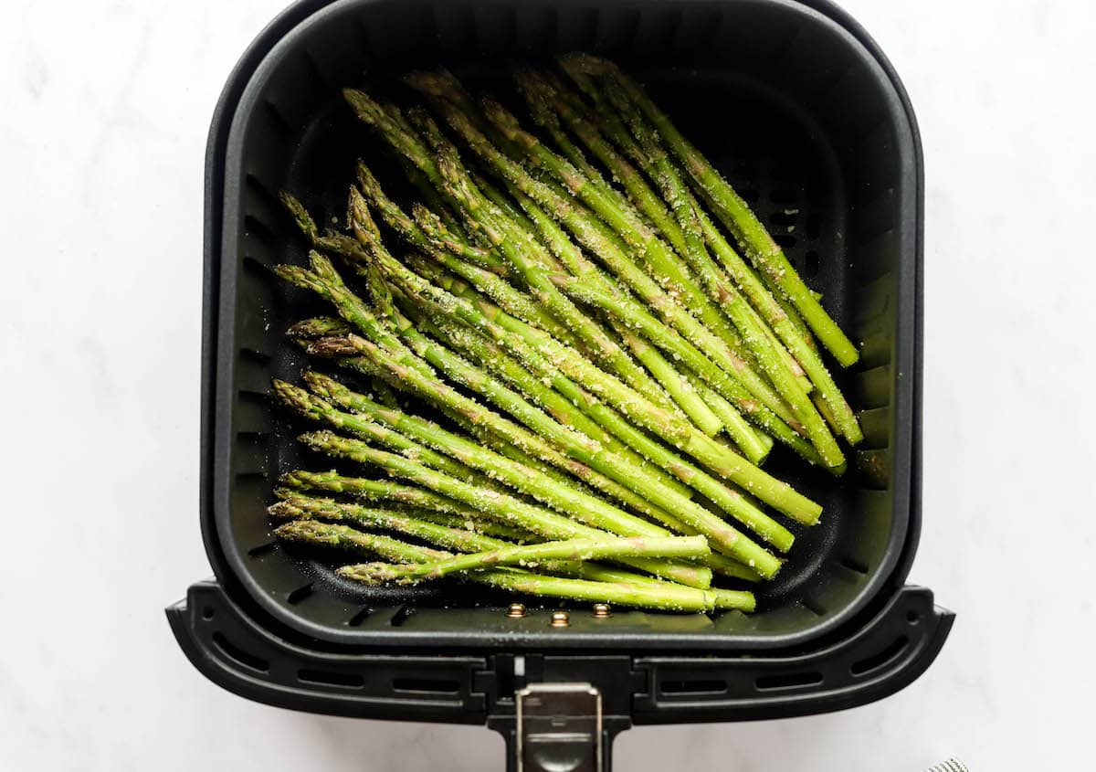 Asparagus spears in an air fryer basket.