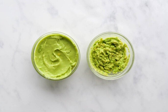 Two jars side by side: one containing avocado puree and the other containing mashed avocado.