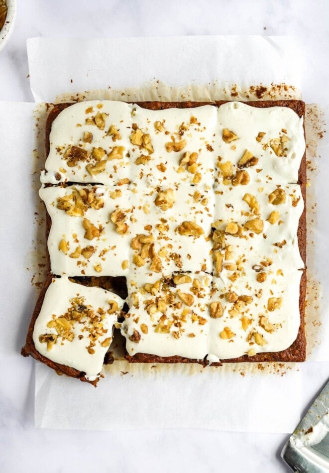 An over head view of carrot cake bars topped with vanilla icing and walnuts.