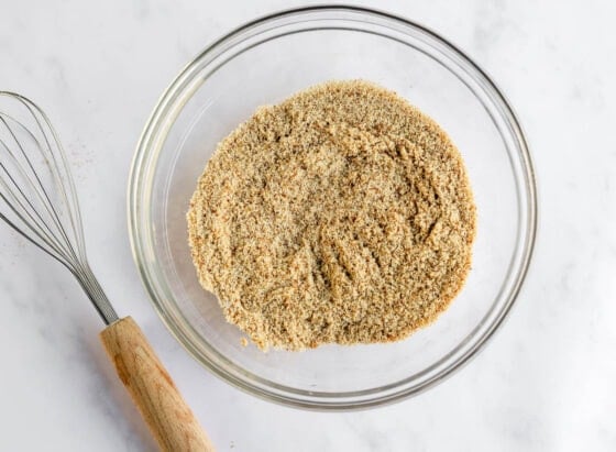 Whisking together almond flour, coconut sugar, baking powder, baking soda, cinnamon, and salt in a bowl.