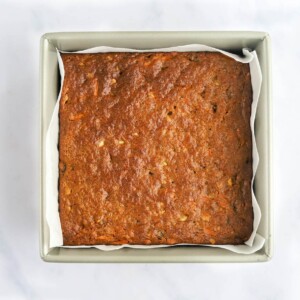 Freshly baked carrot cake bars in a parchment lined baking pan.