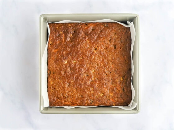Freshly baked carrot cake bars in a parchment lined baking pan.