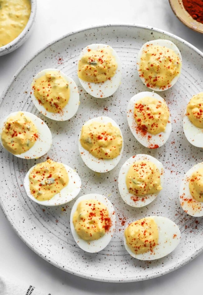 A serving plate with healthy deviled eggs sprinkled with paprika.