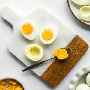 Scooping the yolk from halved hard boiled eggs.