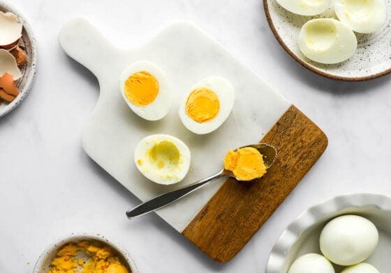Scooping the yolk from halved hard boiled eggs.