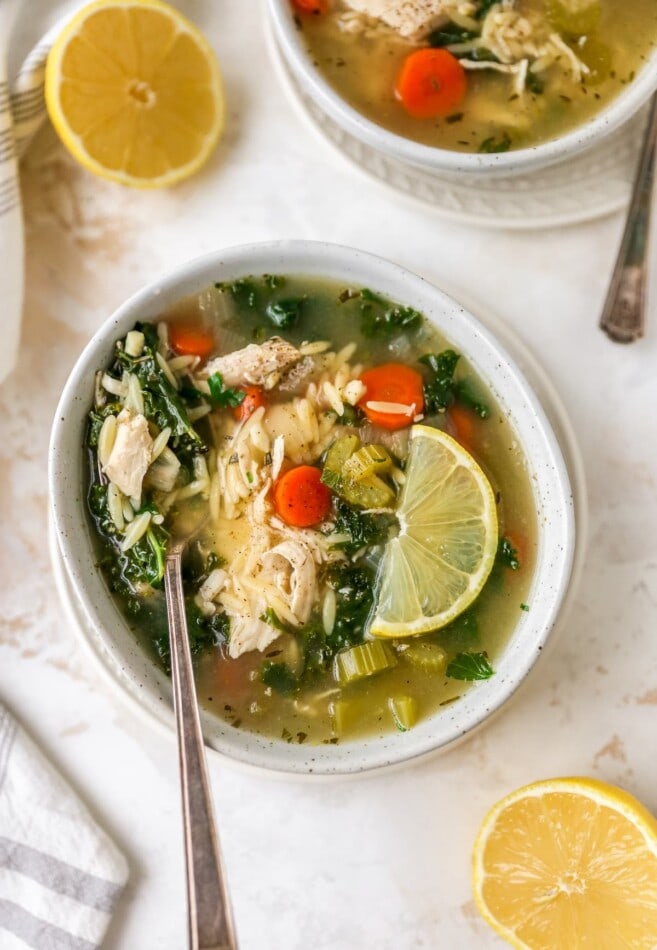 A bowl of lemon chicken orzo soup. A spoon rests in the bowl.