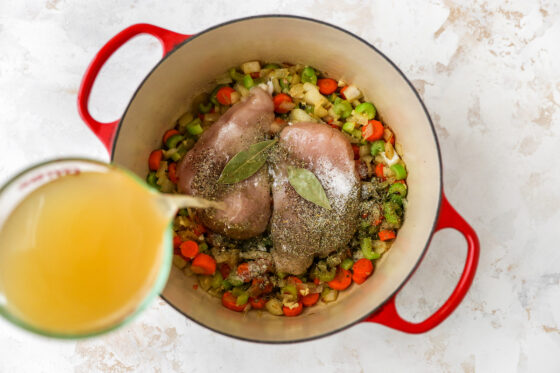 Pouring broth into Dutch oven.