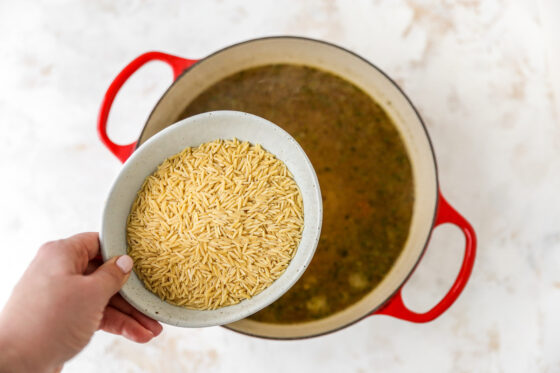 Adding orzo to Dutch oven.