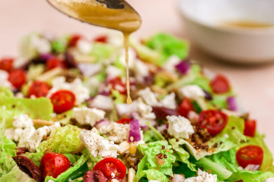 Drizzling dressing onto mediterranean salad.