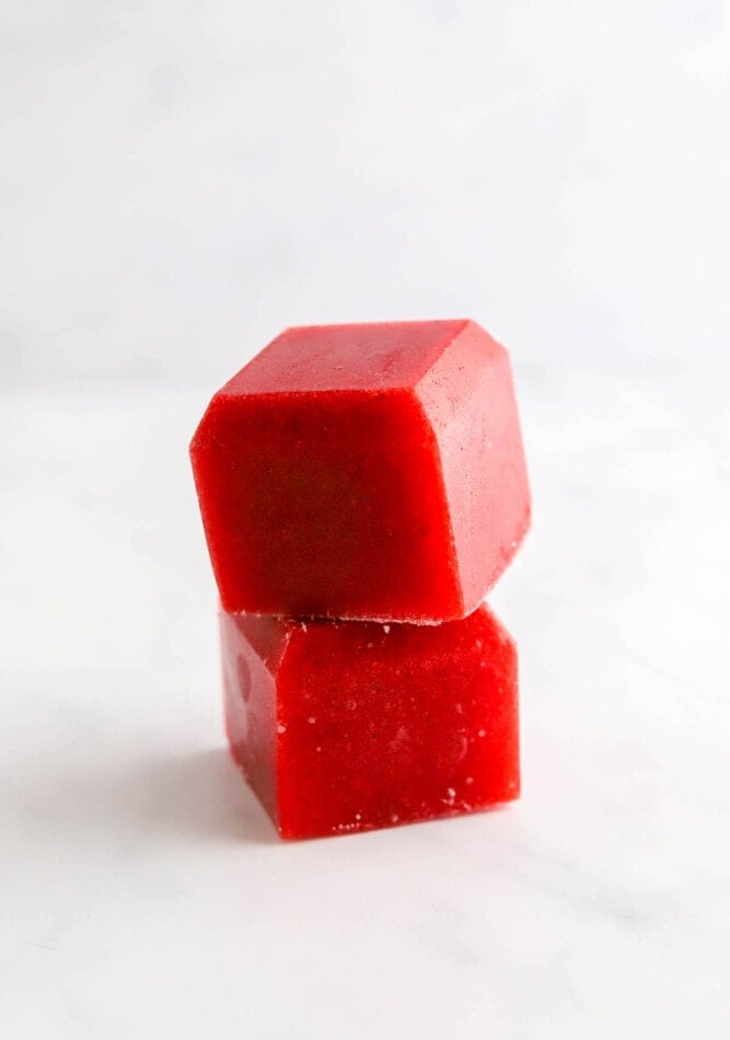 Two cubes of frozen strawberry puree stacked on top of each other.