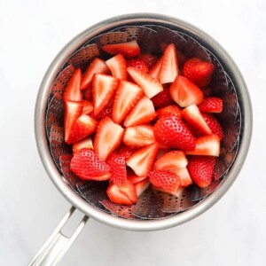 Strawberries in a steamer basket in a pot.