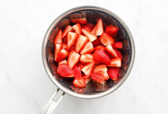 Strawberries in a steamer basket in a pot.