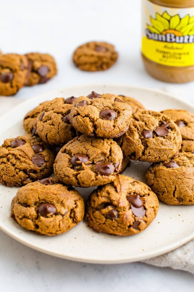 A plate cookies piled on top of each other. A SunButter nut butter container is in the background.