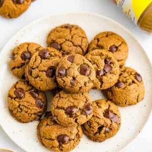 A plate of SunButter cookies. A container of SunButter sunflower seed butter is laying next to the plate.