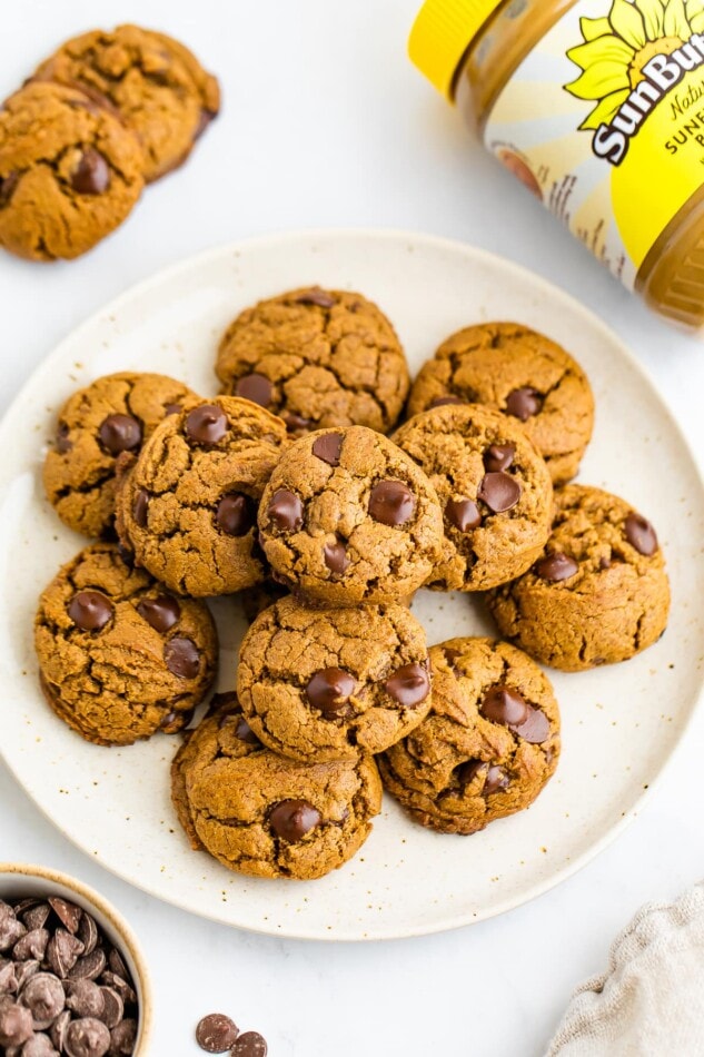 A plate of SunButter cookies. A container of SunButter sunflower seed butter is laying next to the plate.