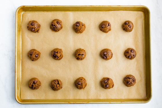 Portioned cookies on a baking sheet lined in parchment paper.